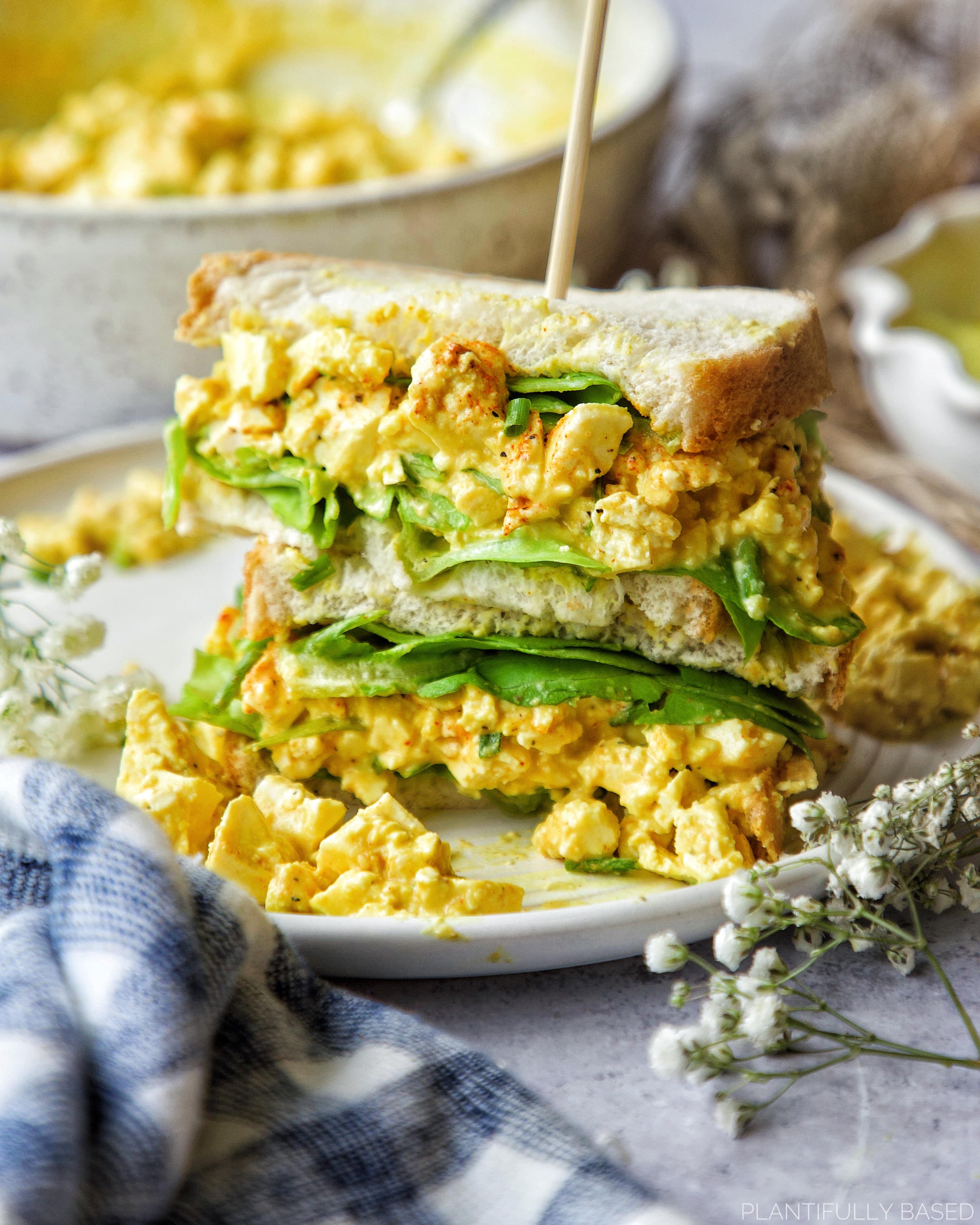 vegan egg salad sandwich cut in half and stacked in top of one another