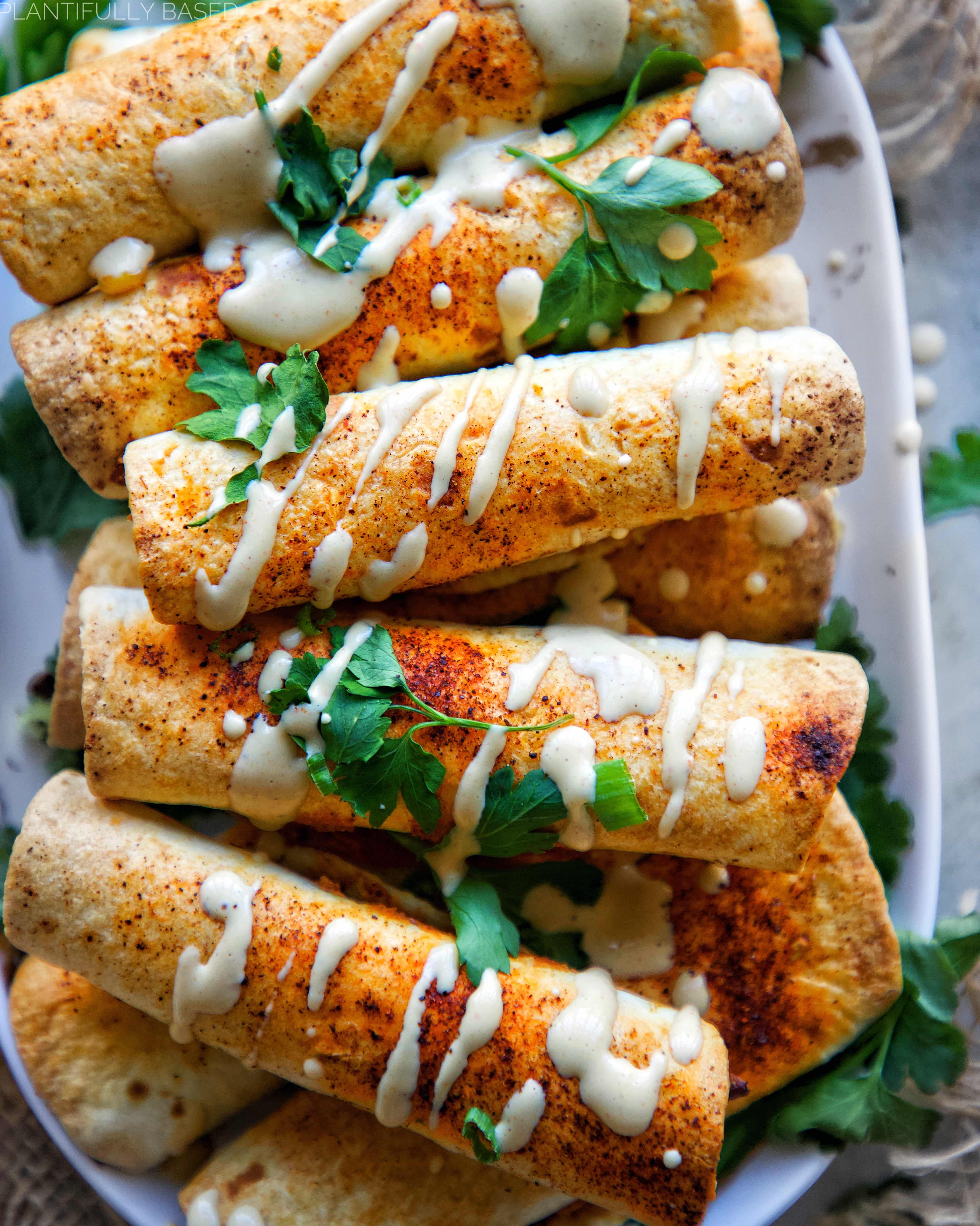 image of flautas drizzled with sauce, birds eye view, laying flat in a dish