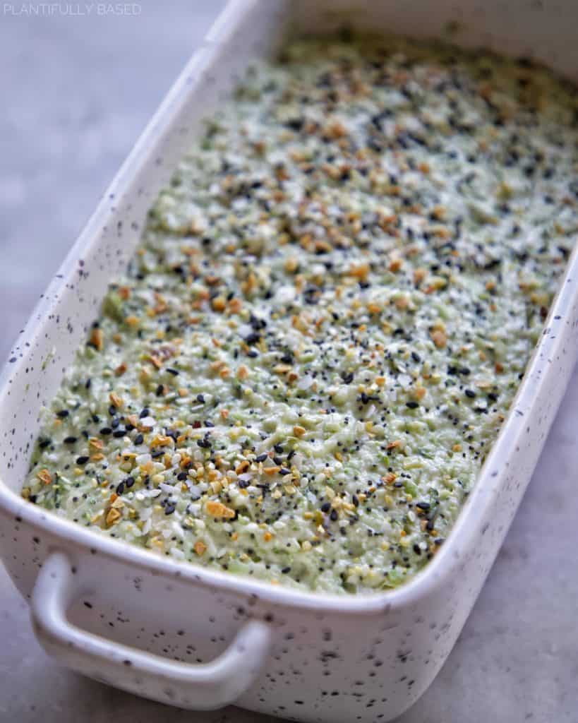 savory zucchini bread in prepared baking loaf pan, prior to baking, with everything bagel seasoning on top