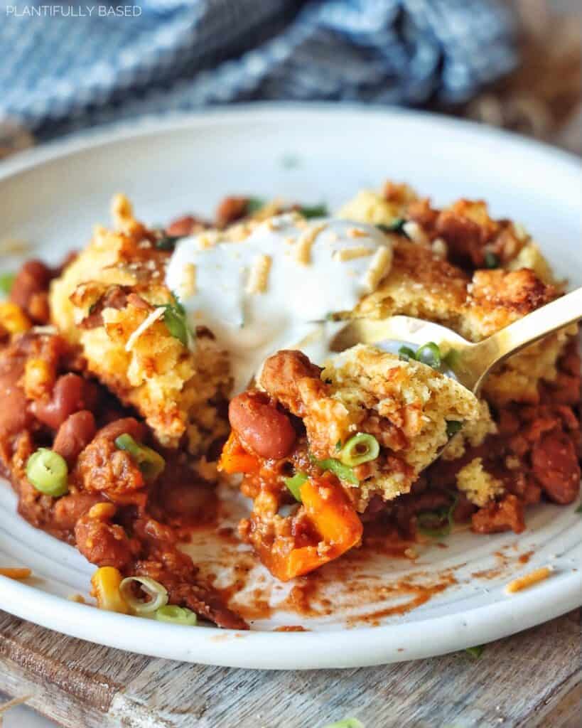 vegan cornbread chili casserole with spoon scooping