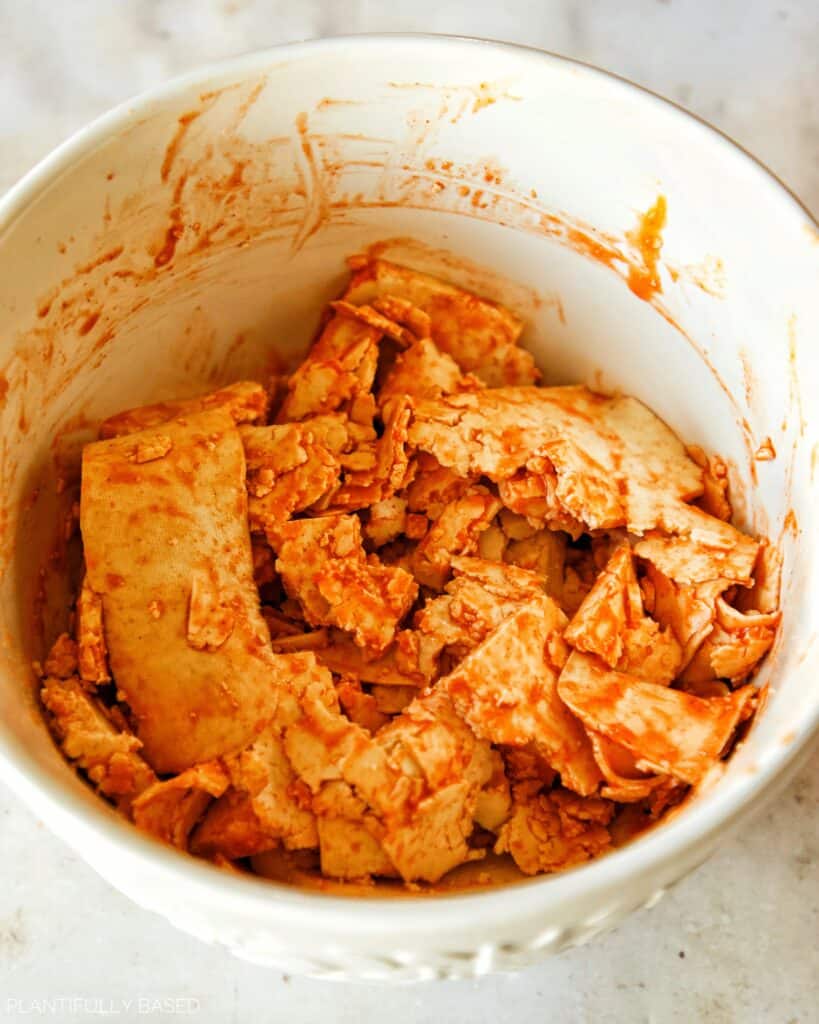 tofu coated in buffalo sauce in a bowl