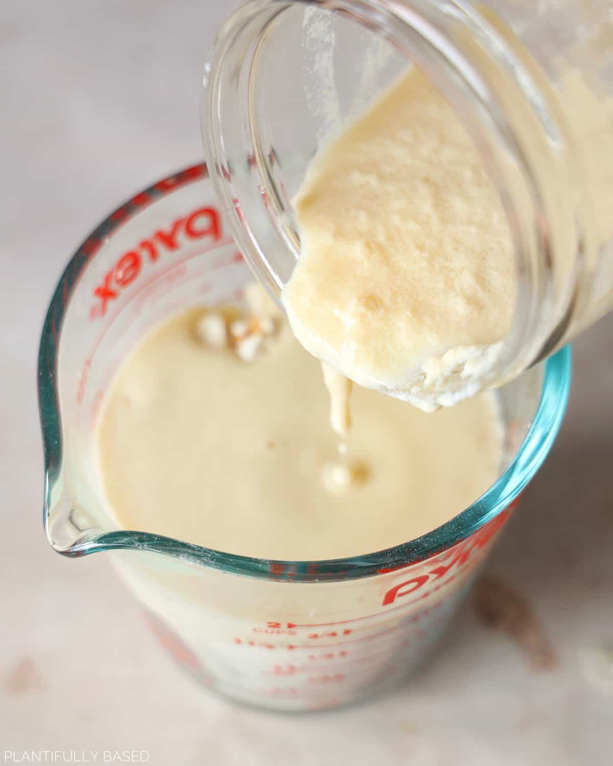vegan buttermilk being poured into measuring cup