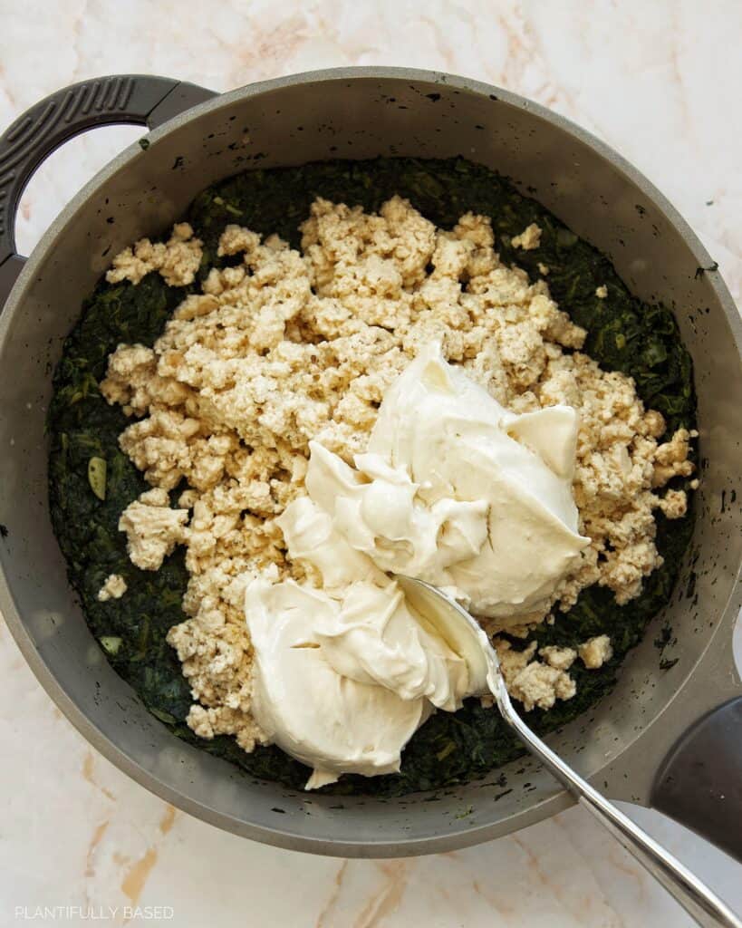 mixing the spinach with tofu feta and vegan cream cheese