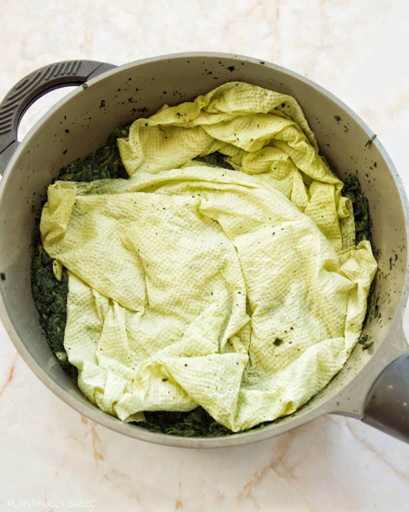 cooked spinach with paper towels for removing excess liquid