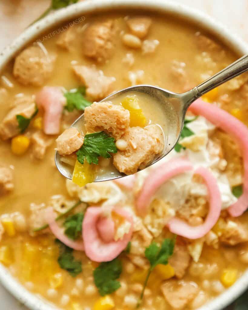 garnished bowl with a small spoon holding a spoonful of chili